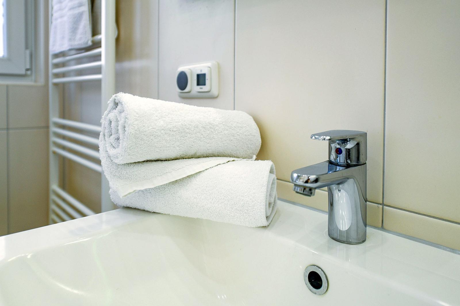 Waschbecken mit Spüle, Wasserhahn und zwei weißen Handtüchern.