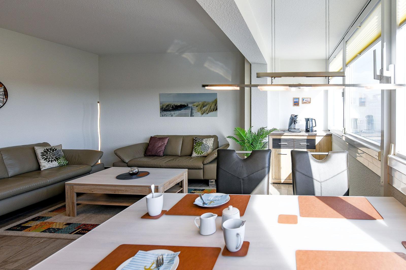 Wohn- und Essbereich mit Sofa, Tisch und Küchenzeile. Fenster mit Blick.