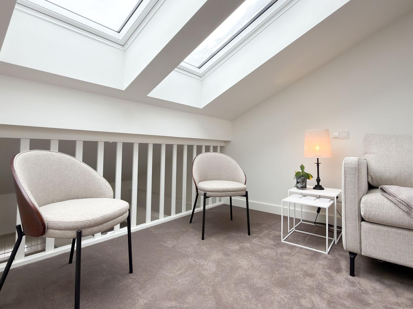 Room with two chairs, armchair and table under skylights.