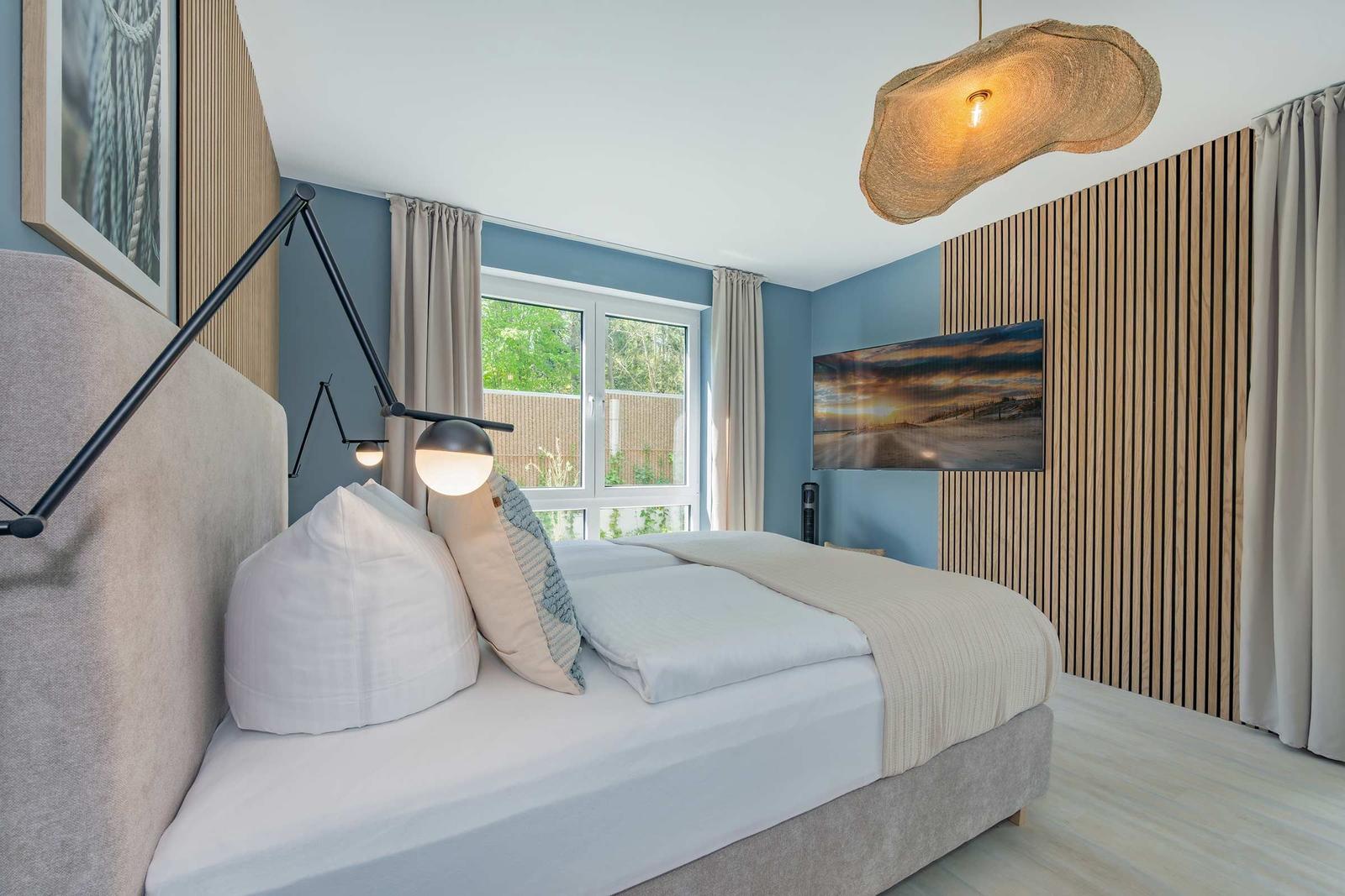 Schlafzimmer mit Bett, Fenster und Wandbild.