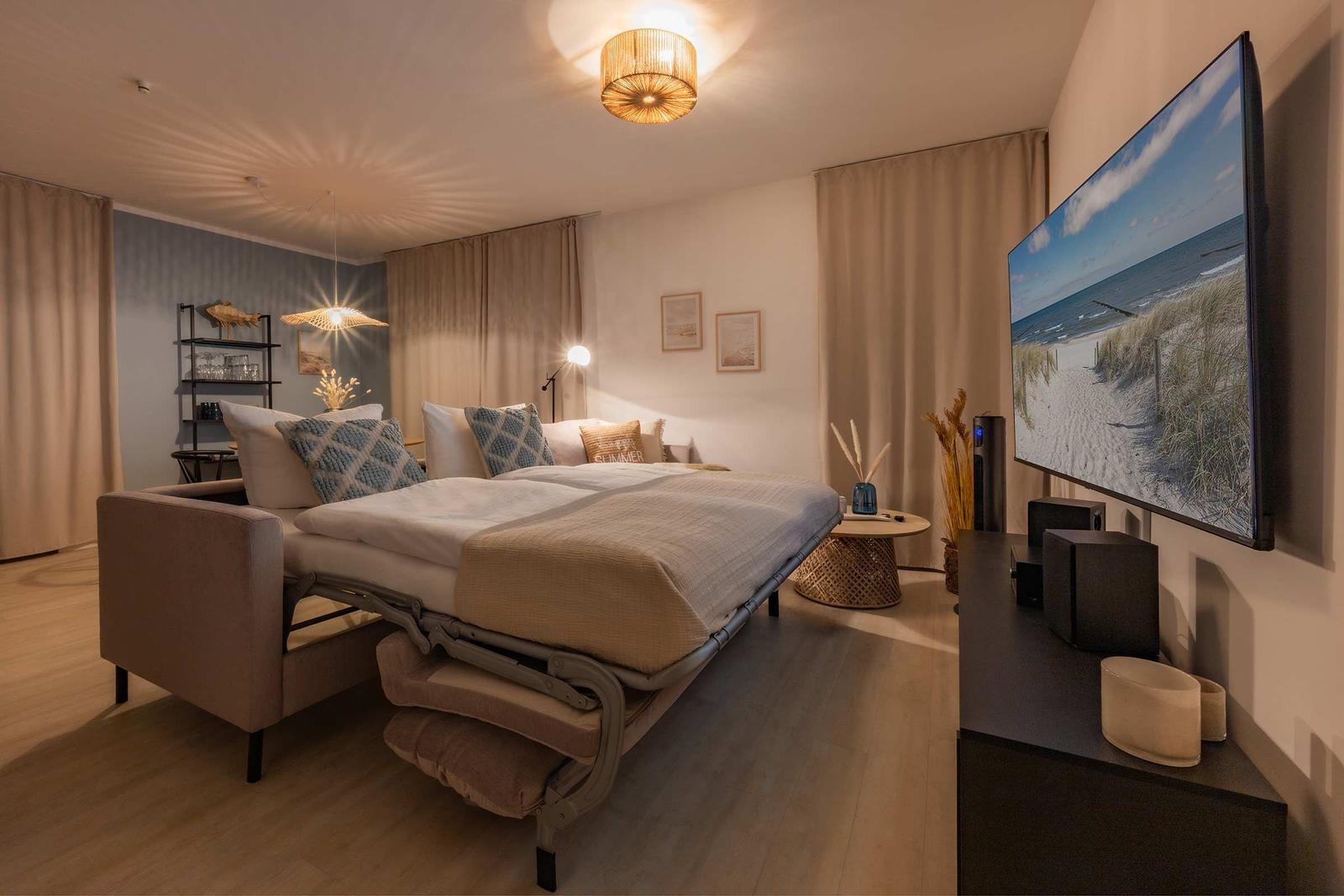 Schlafzimmer mit Bett, Fernseher und dekorativen Elementen.