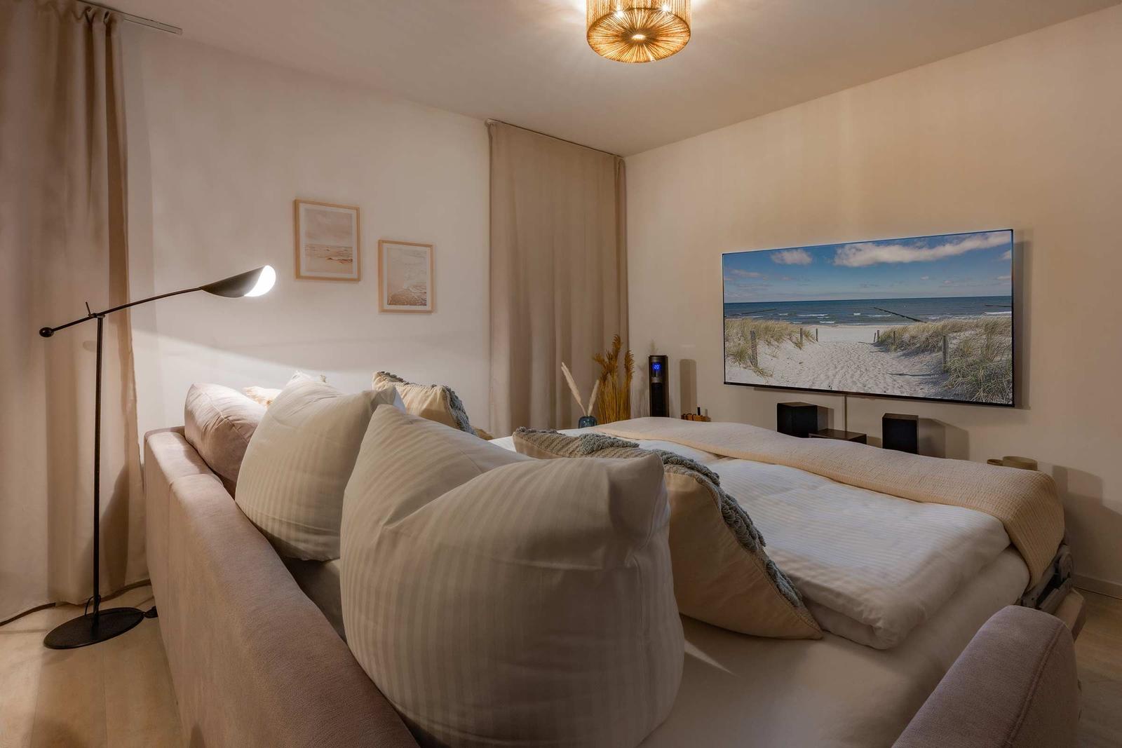 Schlafzimmer mit Bett, Wandbild und Stehlampe.