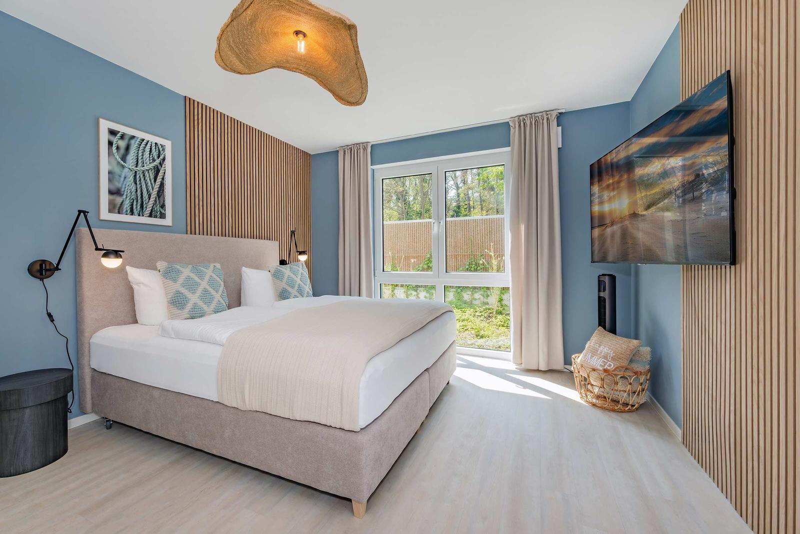 Schlafzimmer mit Bett, Fenster, TV und Holzwand