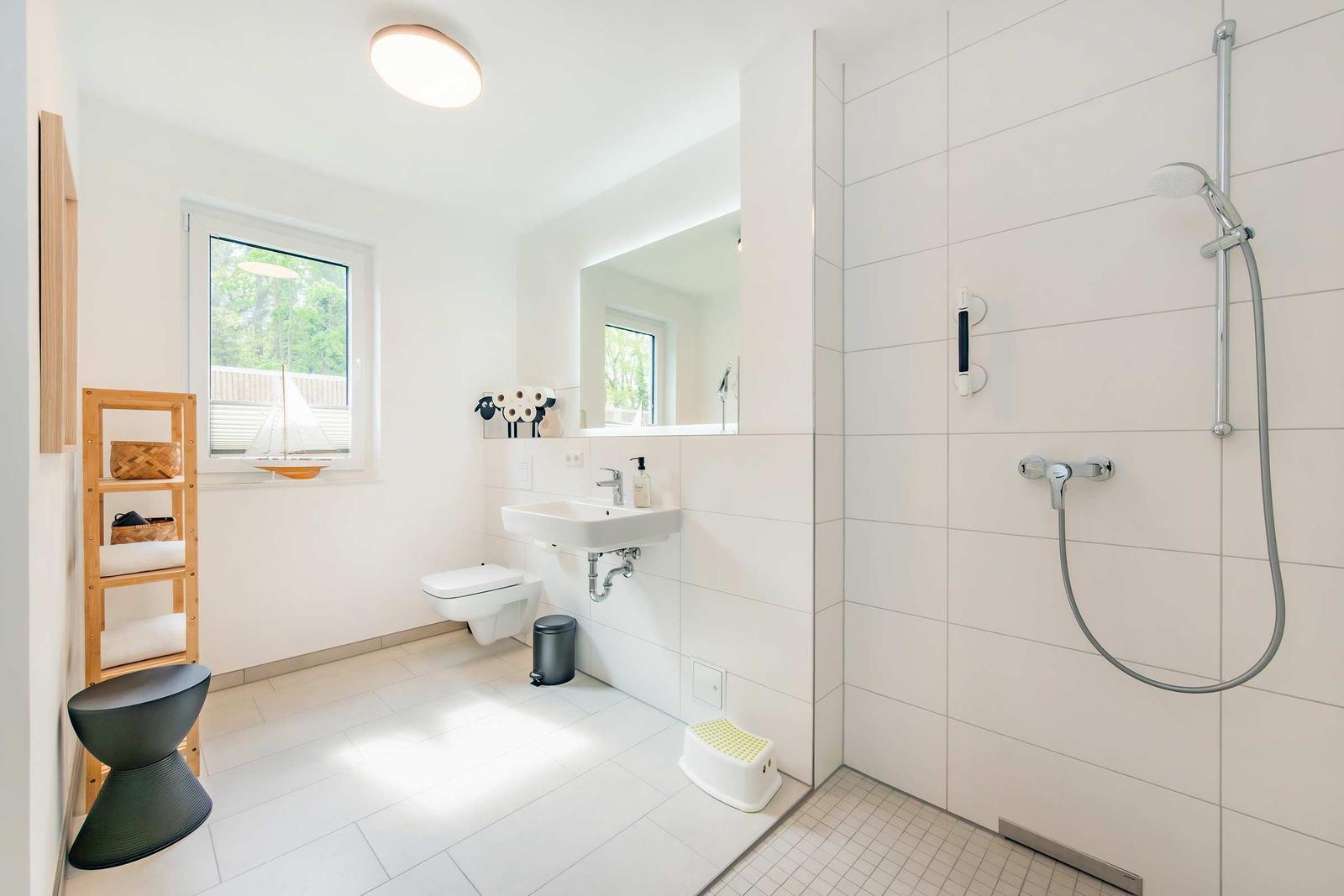 Bad mit Dusche, Waschbecken und Toilette. Fenster, Holzregal und Standfuß.