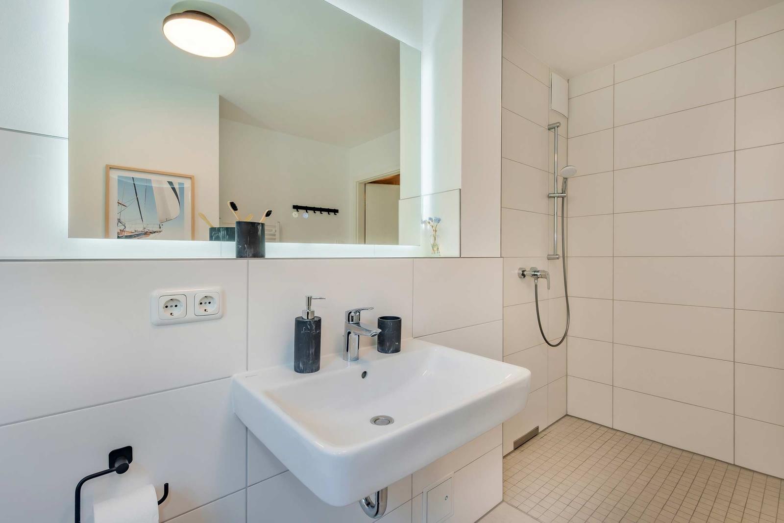 Badezimmer mit Waschbecken, Dusche und Spiegel