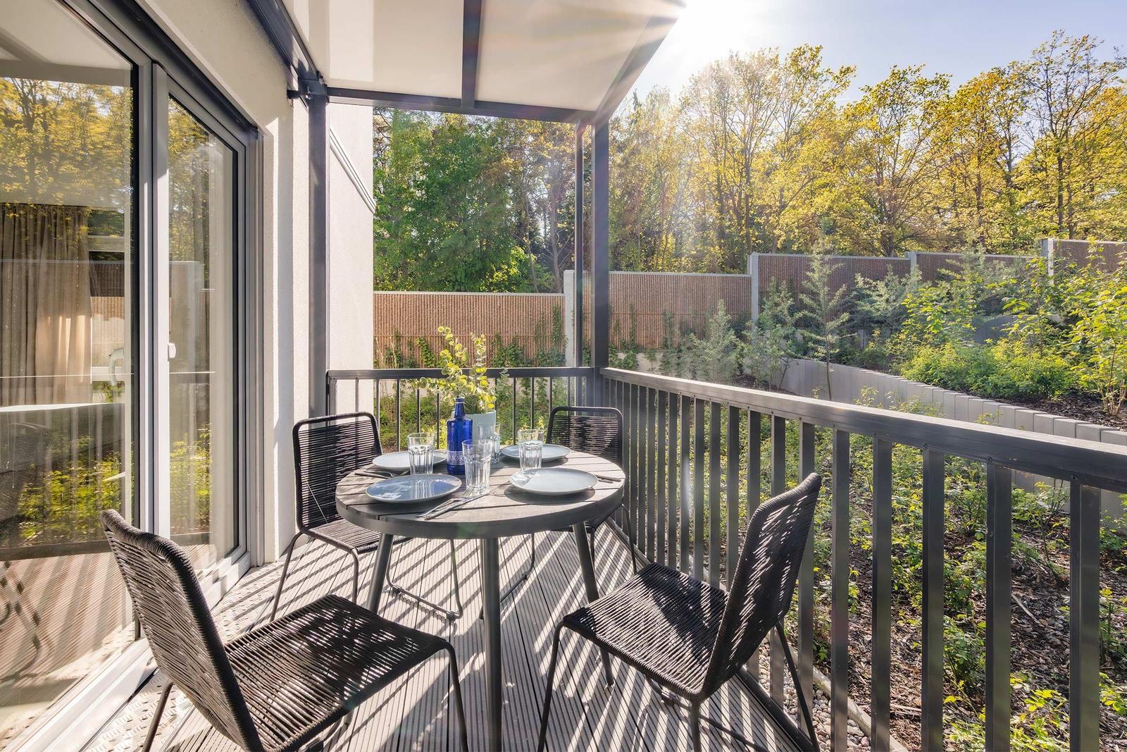 Terrasse mit Tisch und Stühlen, Blick in grüne Umgebung.