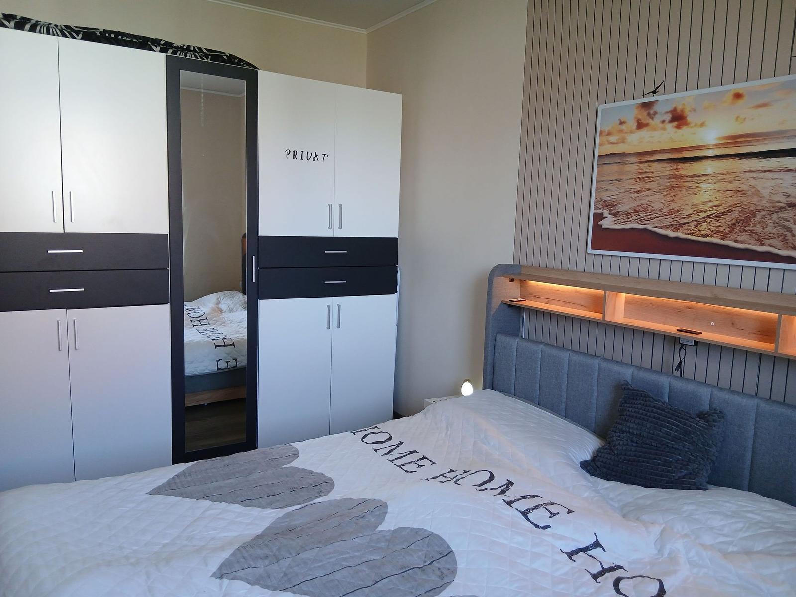 Schlafzimmer mit Bett, Kleiderschrank und Wandbild