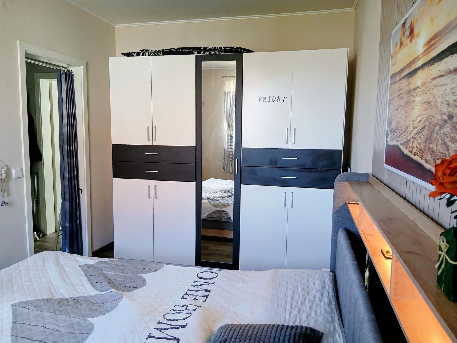 Schlafzimmer mit Doppelbett, Kleiderschrank und Wandbild.
