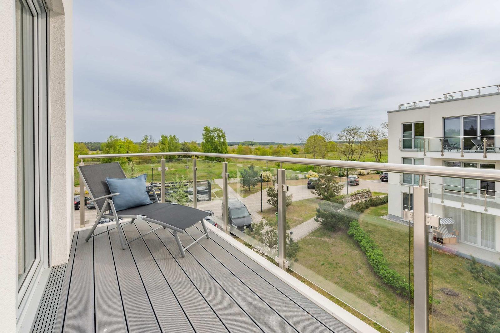Terrasse mit Liegestuhl und Blick auf Grünflächen und Gebäude
