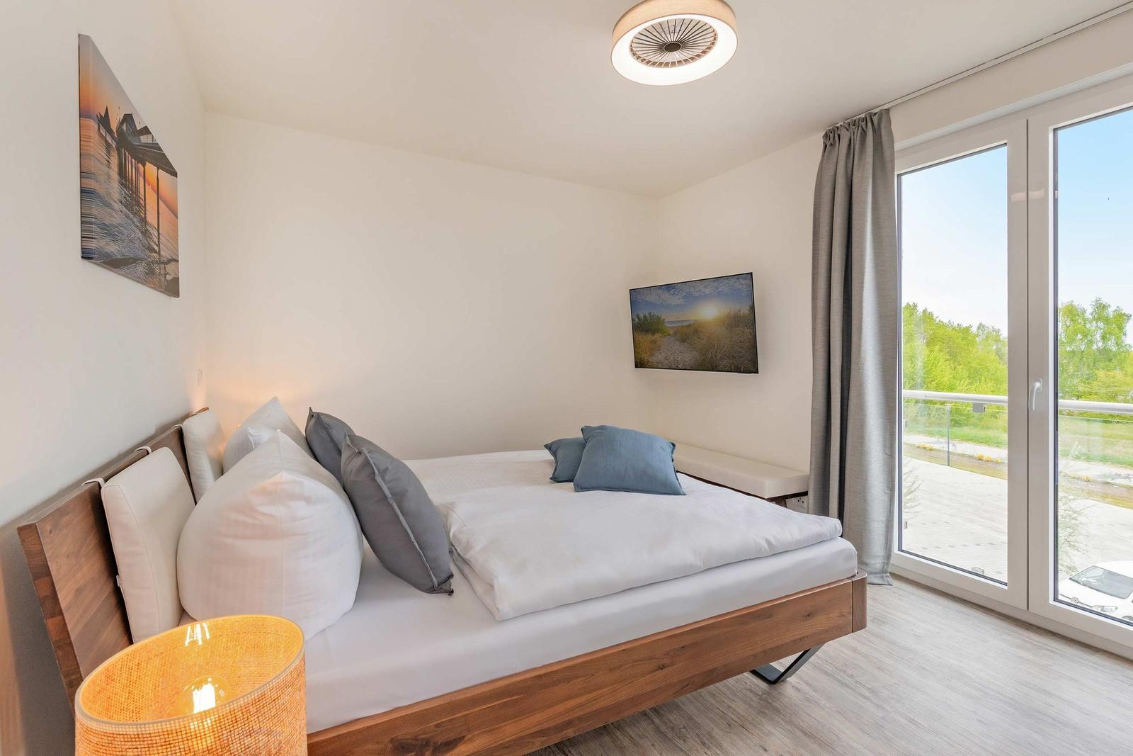 Schlafzimmer mit Bett, Fenster und Wandbildern.