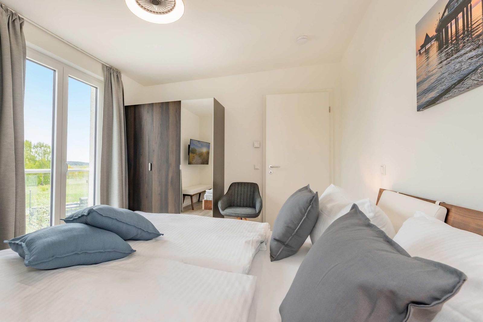 Schlafzimmer mit Doppelbett, Fenster und Wandbild.