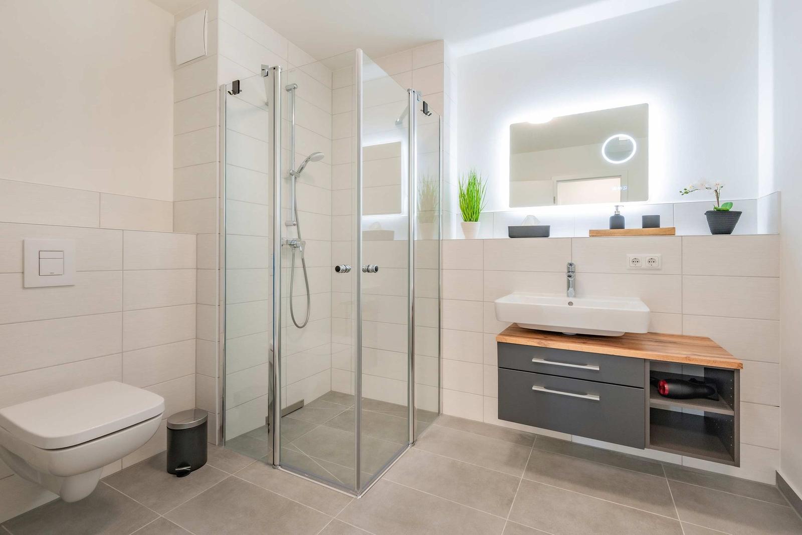 Badezimmer mit Dusche, Waschbecken und Toilette. Moderne Einrichtung mit Holzoberfläche.