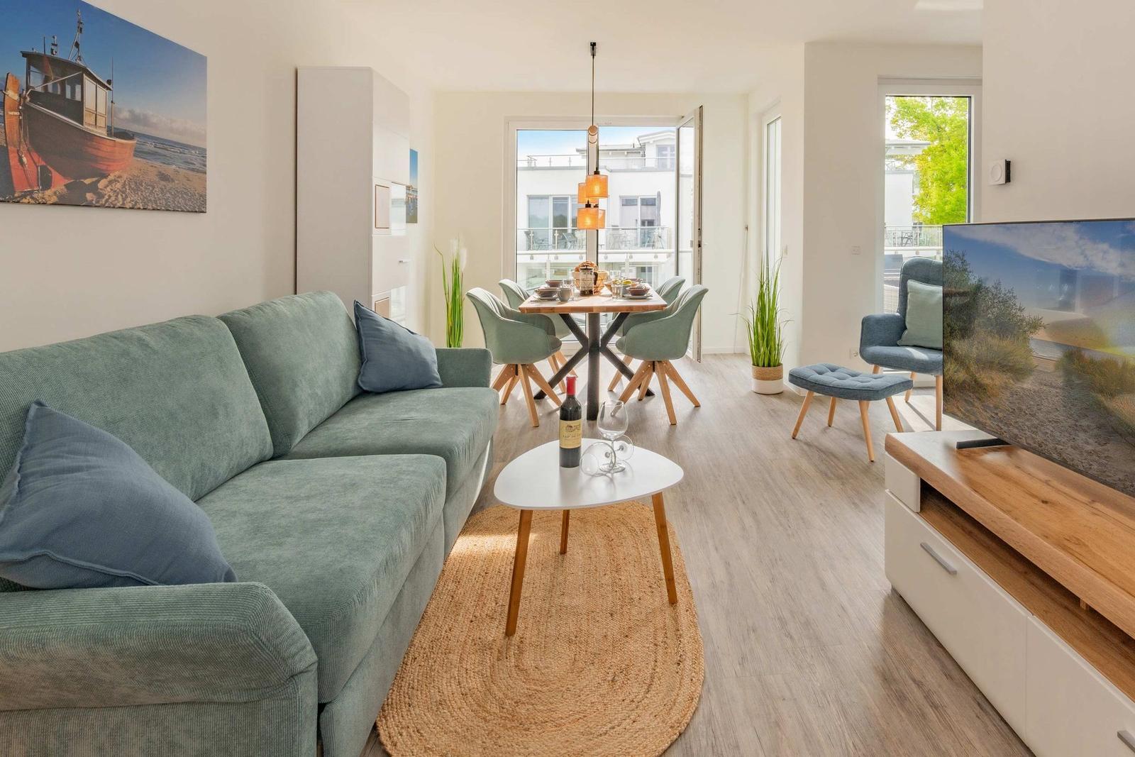 Wohnzimmer mit Sofa, Esstisch und TV. Durchgang zur Terrasse.