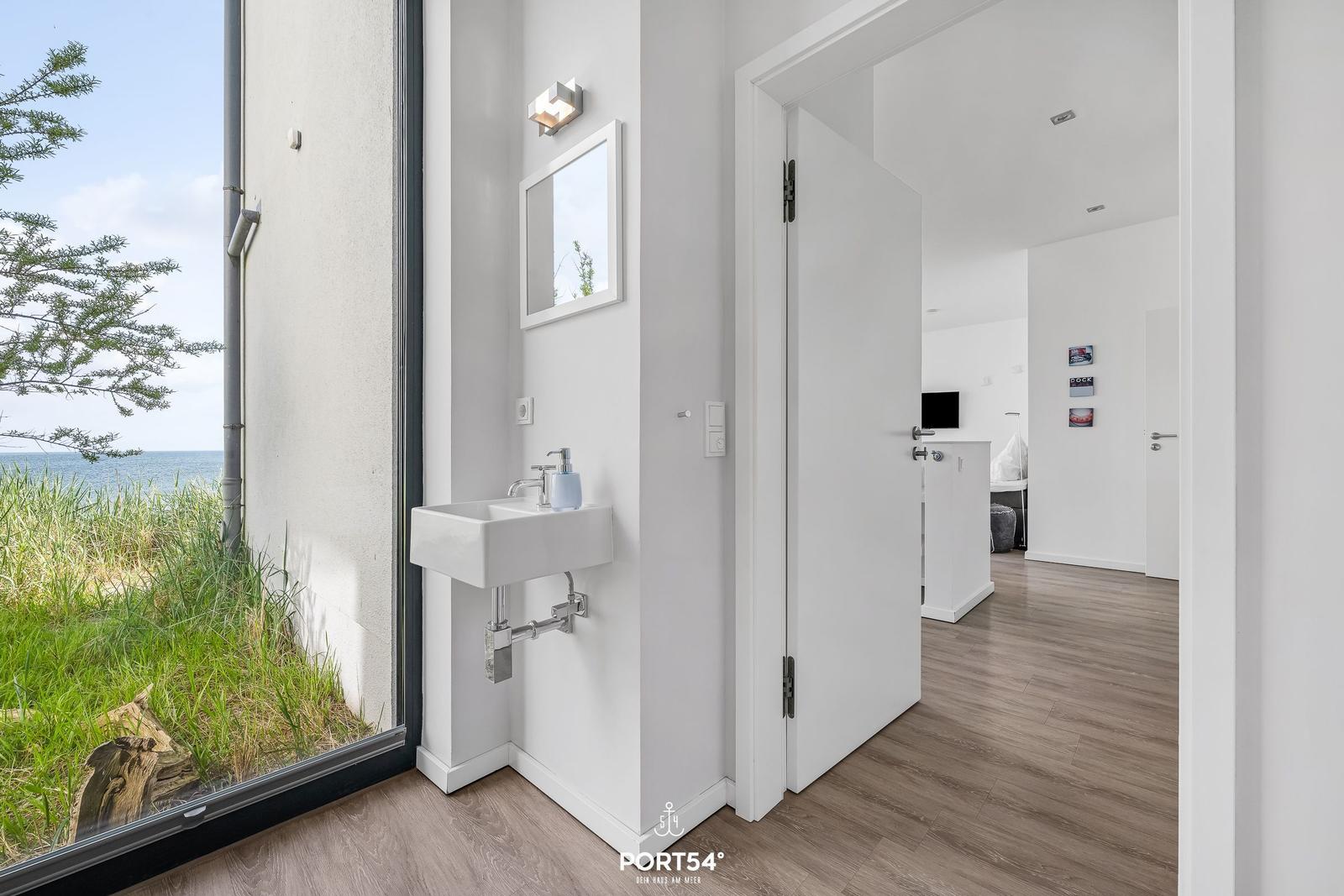 Waschbecken mit Spiegel und Aussicht auf Meer und Grün.