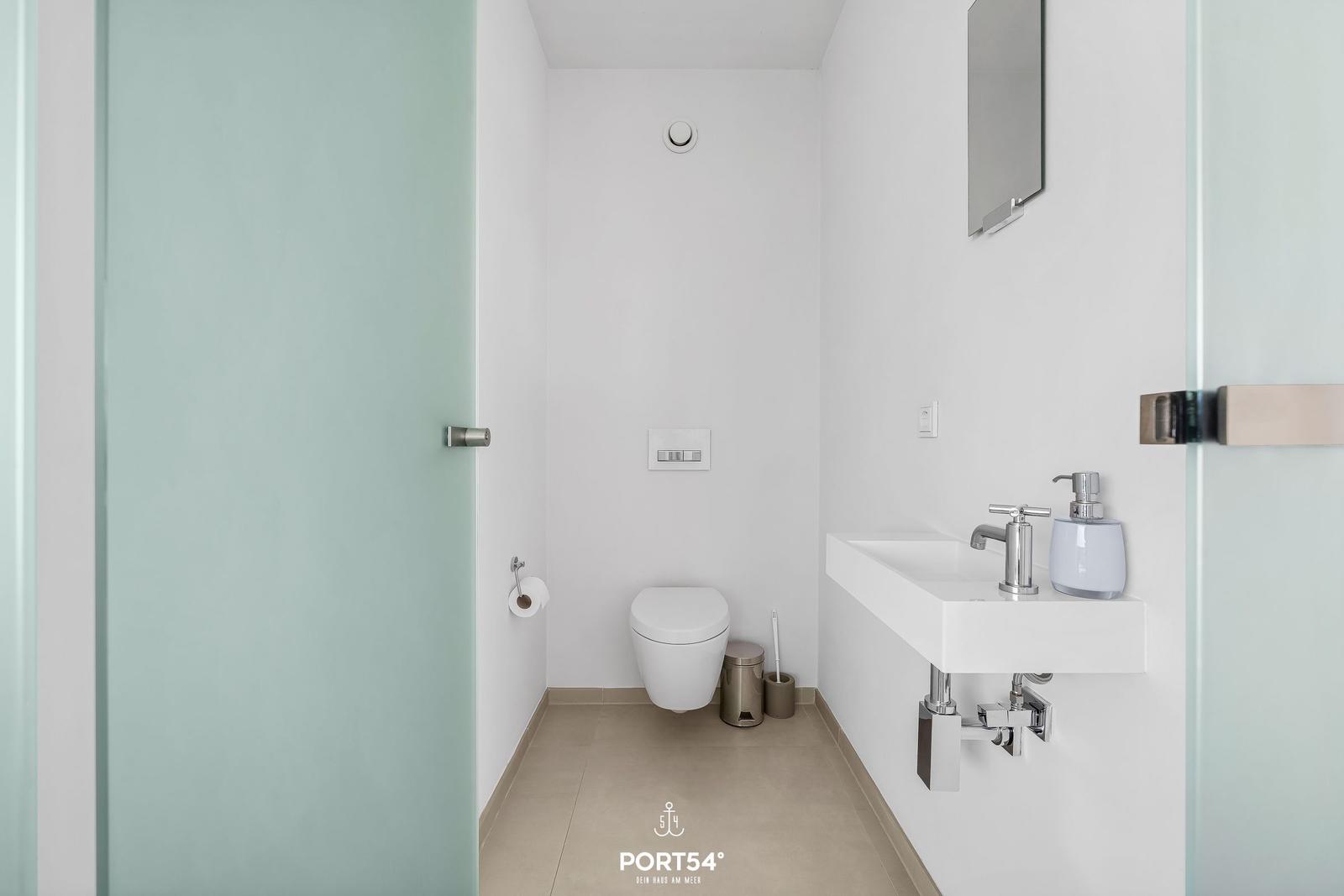 Badezimmer mit Toilette, Waschbecken und Spiegel