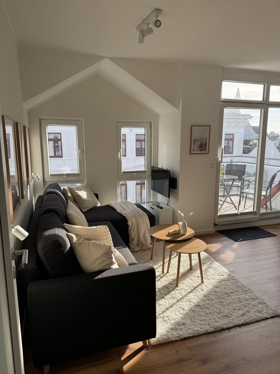 Wohnzimmer mit Sofa, Tischen und Blick auf Balkon