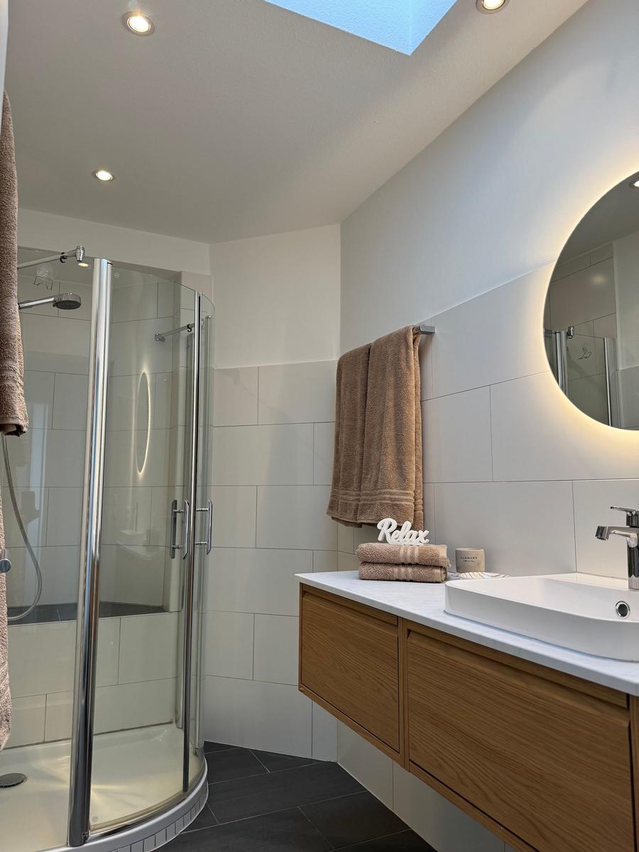 Badezimmer mit Dusche, Waschbecken und Spiegel