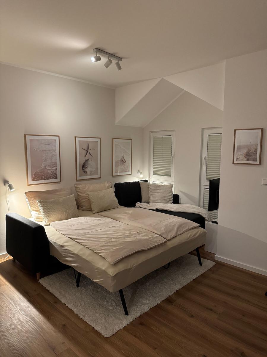 Schlafzimmer mit Doppelbett, Wandbildern und Holzboden.