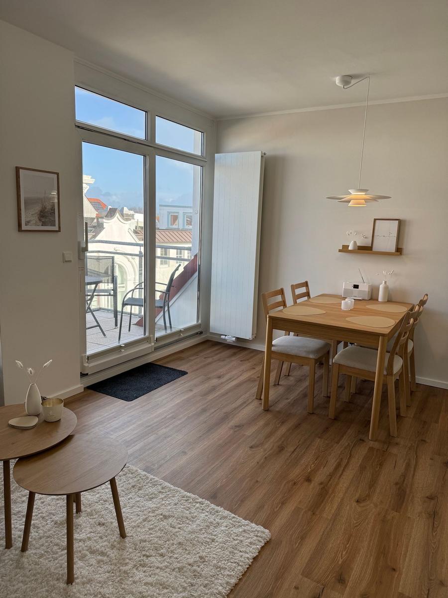 Essbereich mit Holztisch, Stühlen und großem Fenster zum Balkon.