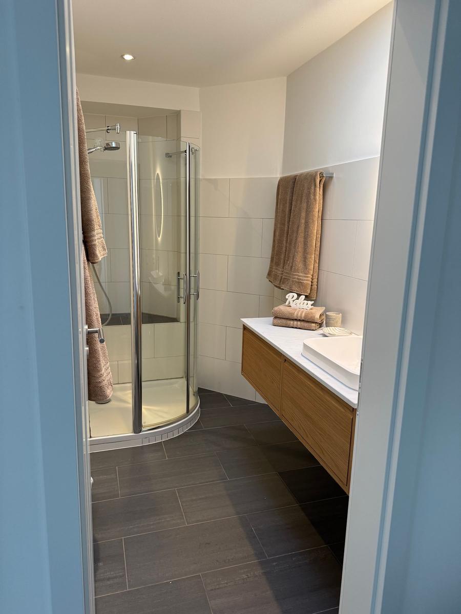 Badezimmer mit Dusche, Waschtisch und Handtüchern.