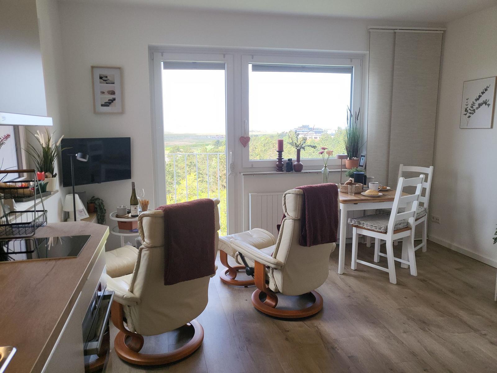 Living area with seating, dining table, and balcony view