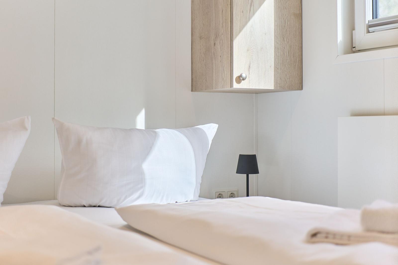 Schlafzimmer mit Bett, Kissen und Wandregal.
