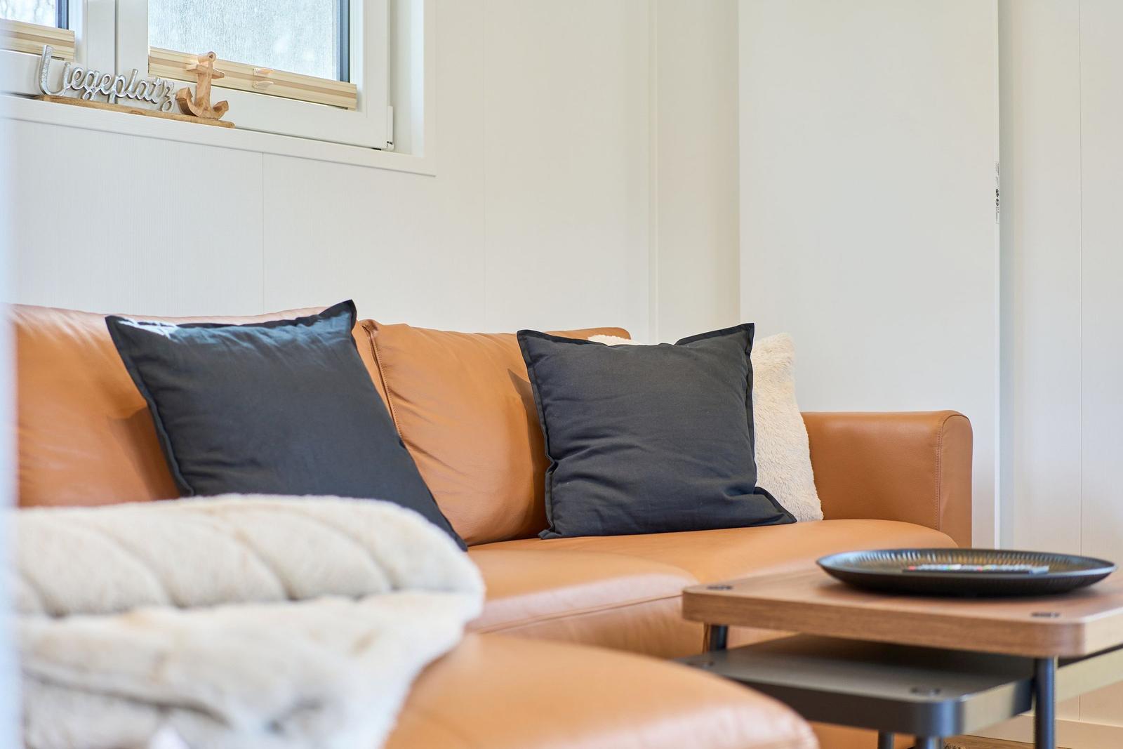 Orange Ledersofa mit Kissen und Tisch im Wohnbereich.
