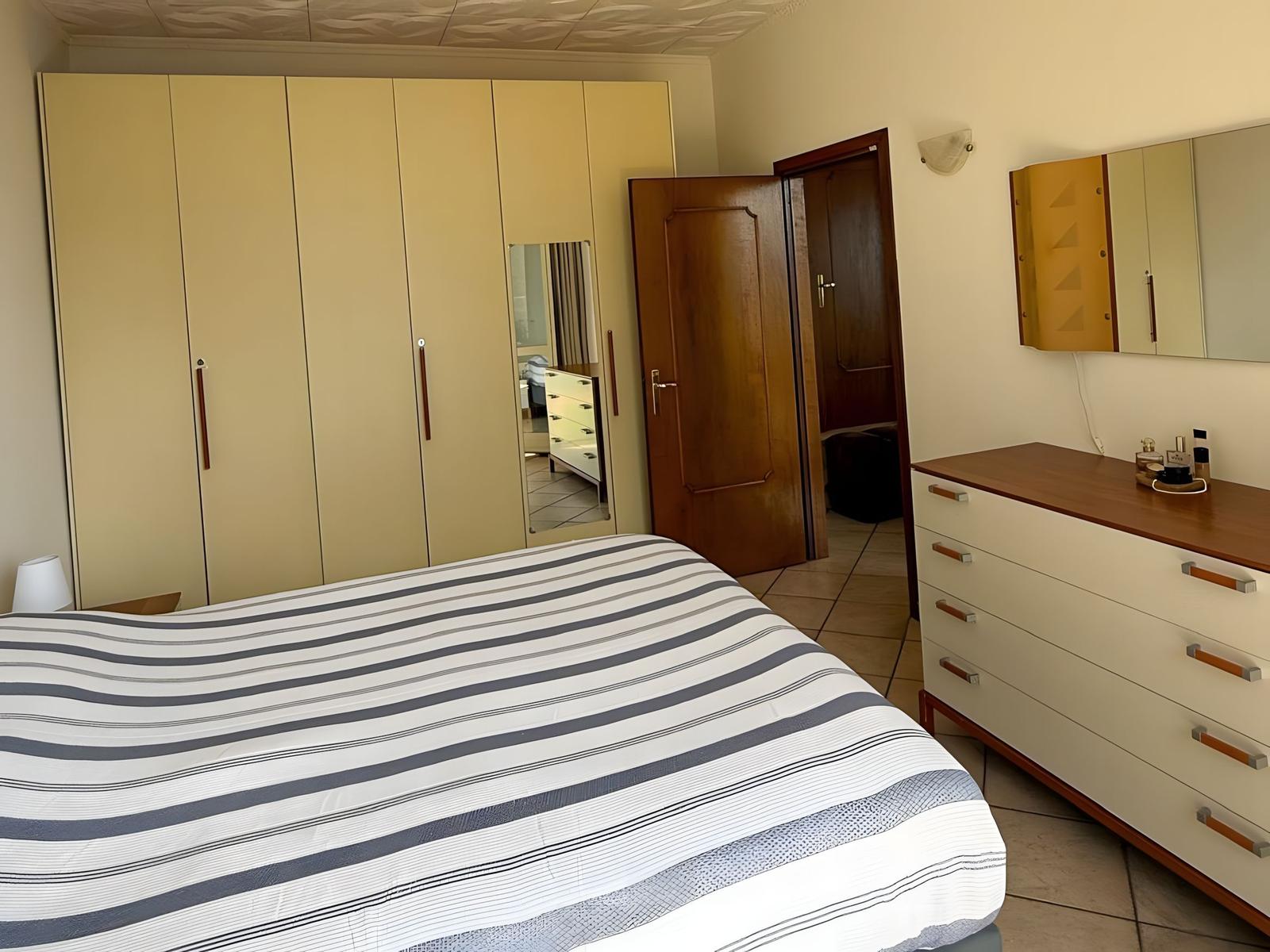 Schlafzimmer mit Bett, Schrank und Schminktisch.