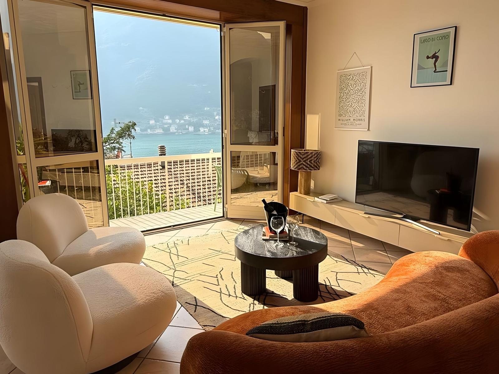 Wohnzimmer mit Blick auf den See, zwei Sessel und Fernseher.