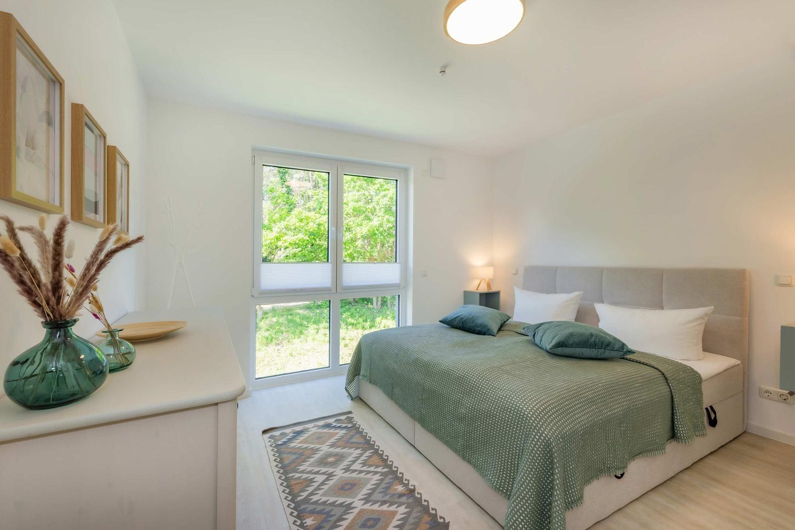Schlafzimmer mit Bett, Fenster und dekorativen Elementen