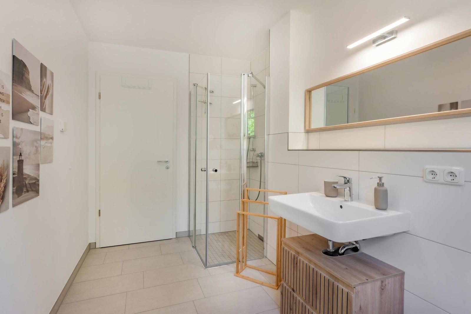 Badezimmer mit Dusche, Waschbecken und Spiegel