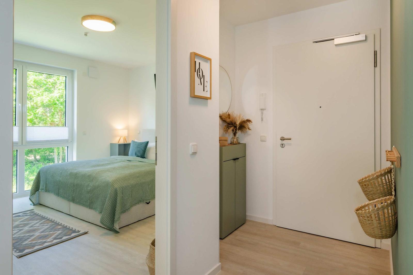 Schlafzimmer mit Bett und Fenster. Flur mit Tür, Schrank und Körben.