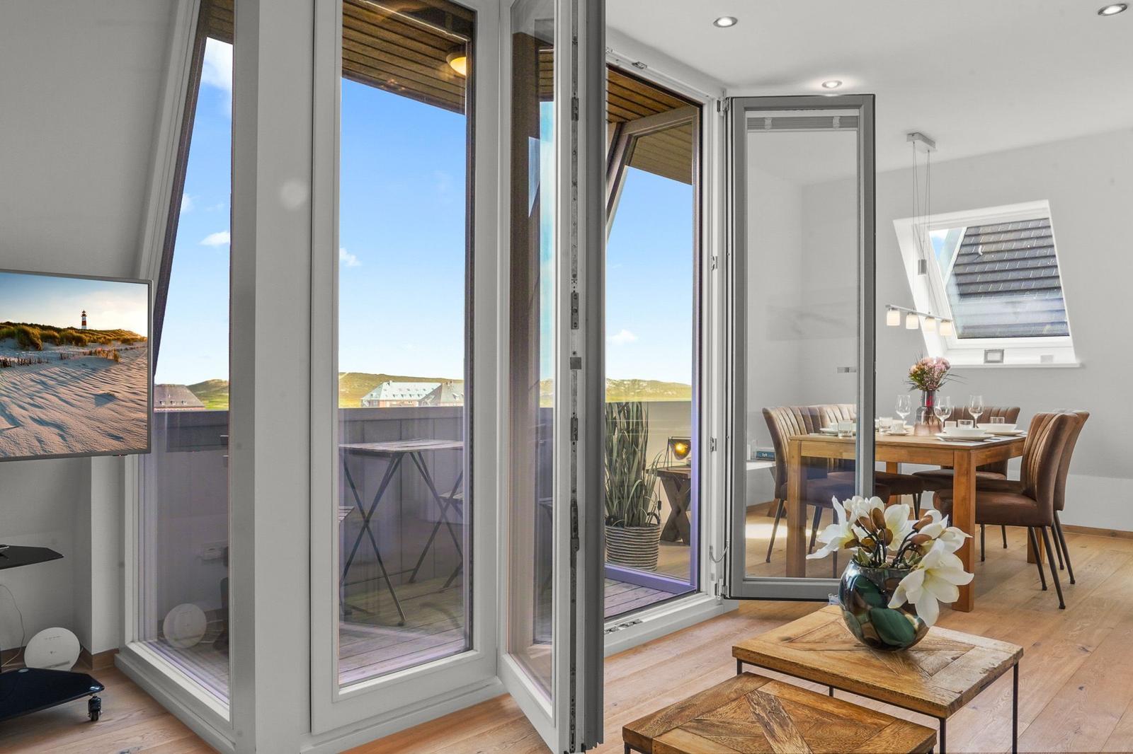 Große Fensteröffnung zum Balkon mit Blick auf den Strand und das Meer.