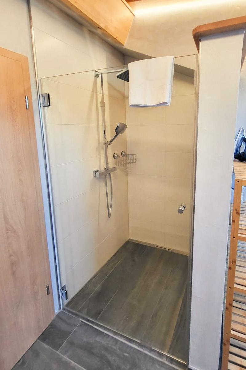 Shower with glass enclosure, handheld shower, and towel rack