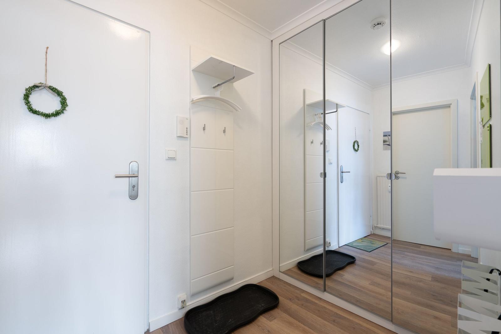 Eingangsbereich mit Spiegelschrank, Tür und kleinem Wandschrank.
