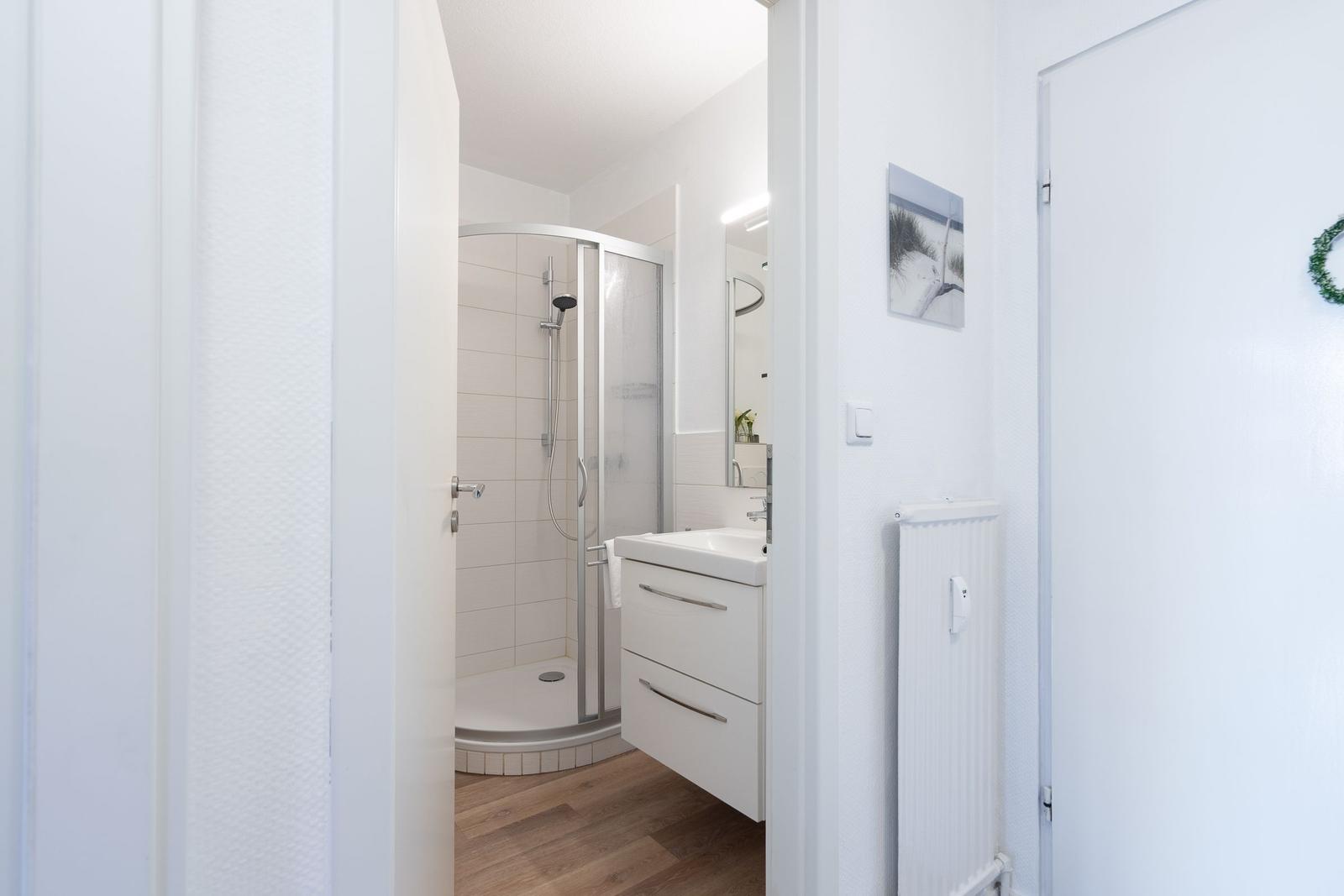 Badezimmer mit Dusche, Waschbecken und Spiegel.