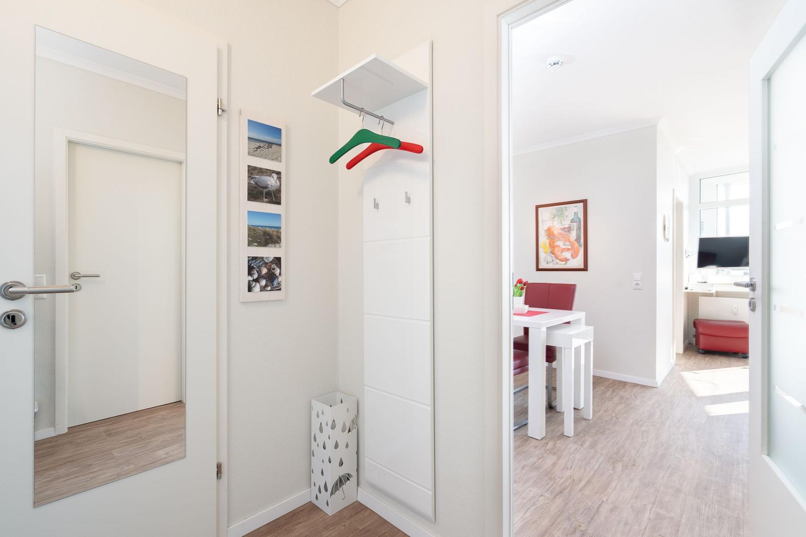Entryway with mirror, coat rack, and view into dining area with table and chairs.
