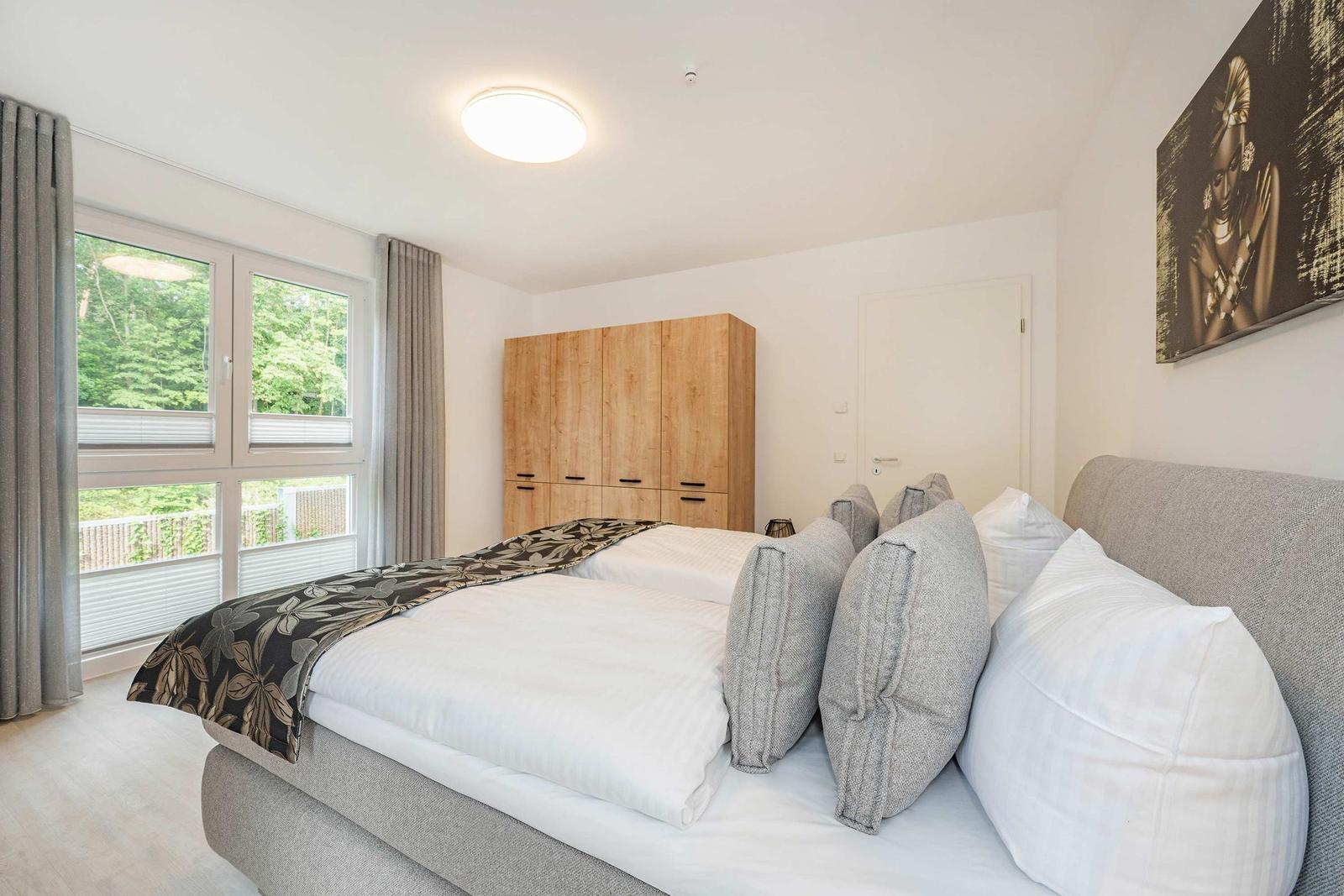 Schlafzimmer mit Bett, Kleiderschrank und Fenster zur Aussicht.