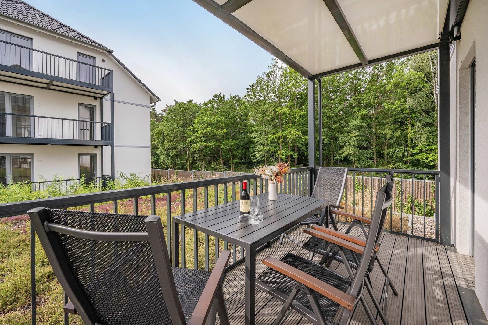 Terrasse mit Tisch, Stühlen und Blick auf Wald.