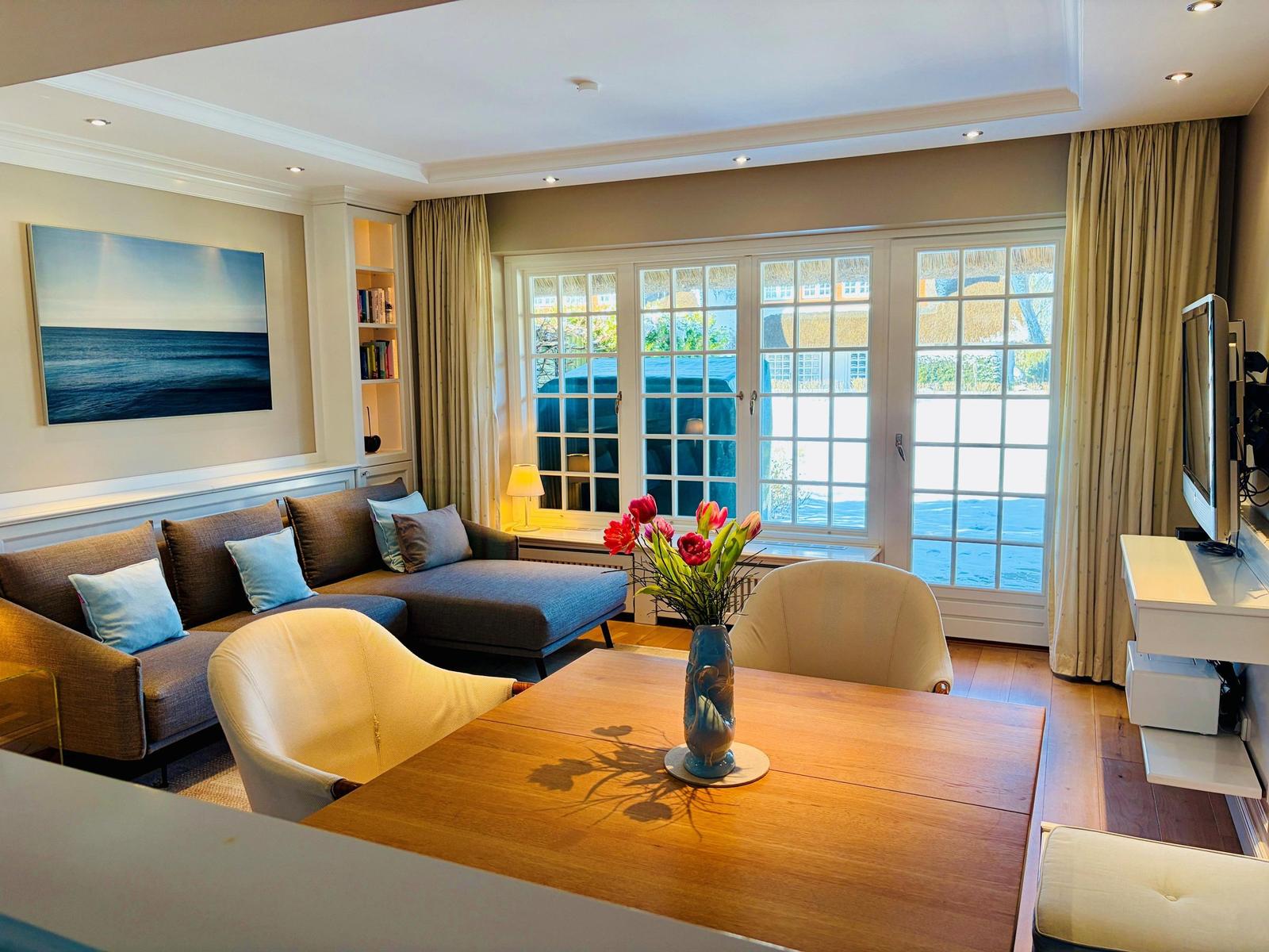 Wohnzimmer mit Sofa, Esstisch und Fenster zur Außenterrasse.