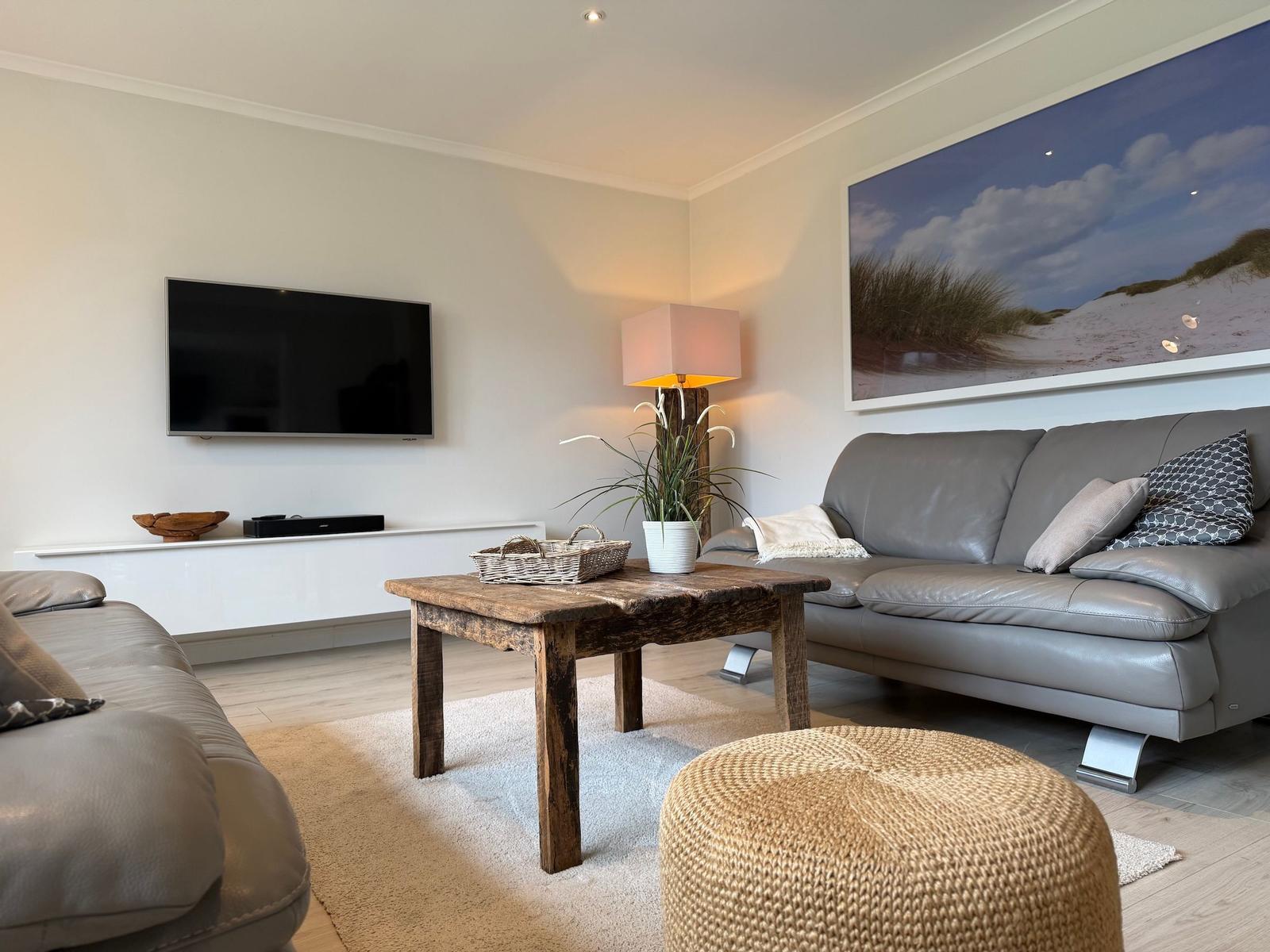 Wohnzimmer mit grauem Sofa, Holztisch und Wandbild