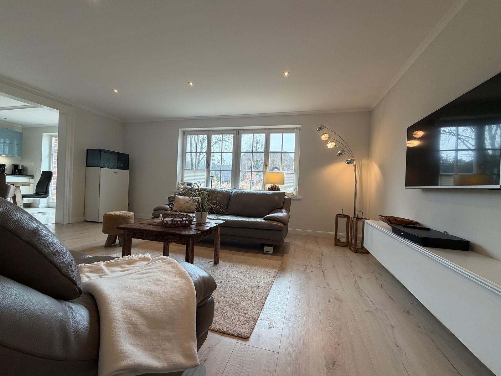 Wohnzimmer mit Ledersofa, Holztisch und Wandfernseher.