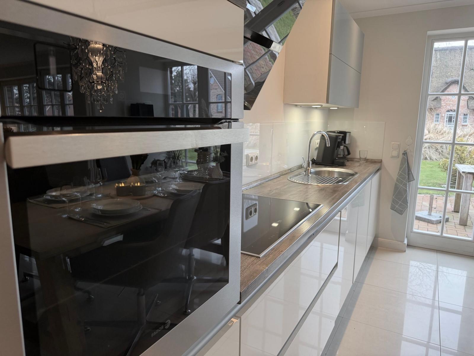 Moderne Küche mit Spüle, Arbeitsfläche und Fenster zur Außenterrasse.