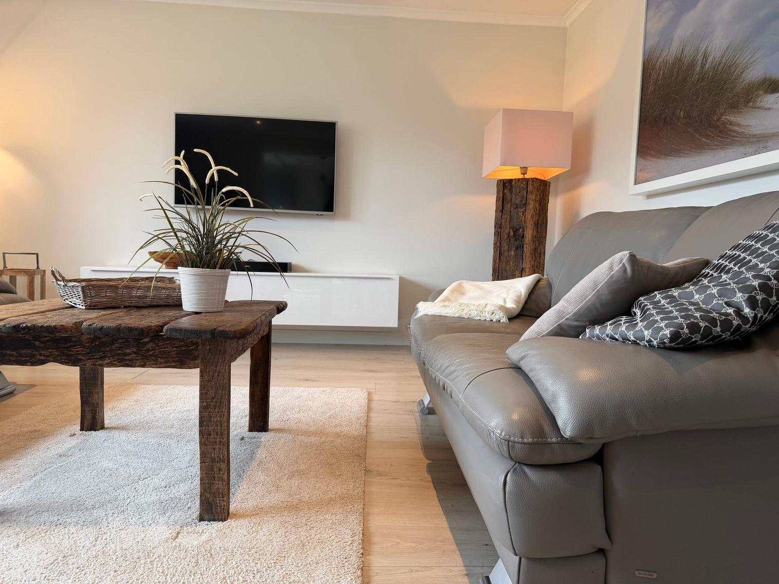 Wohnzimmer mit Sofa, Couchtisch und Fernseher an der Wand.
