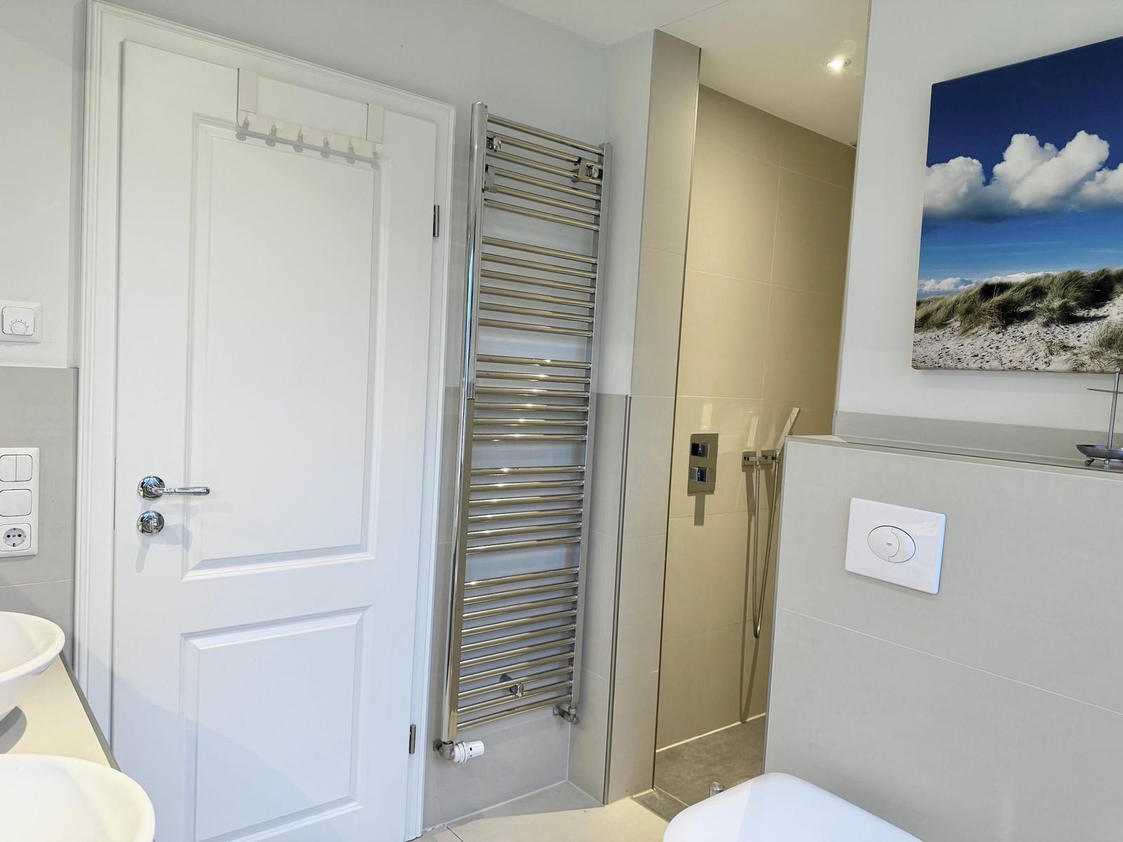 Badezimmer mit Dusche, Heizkörper und Wandbild