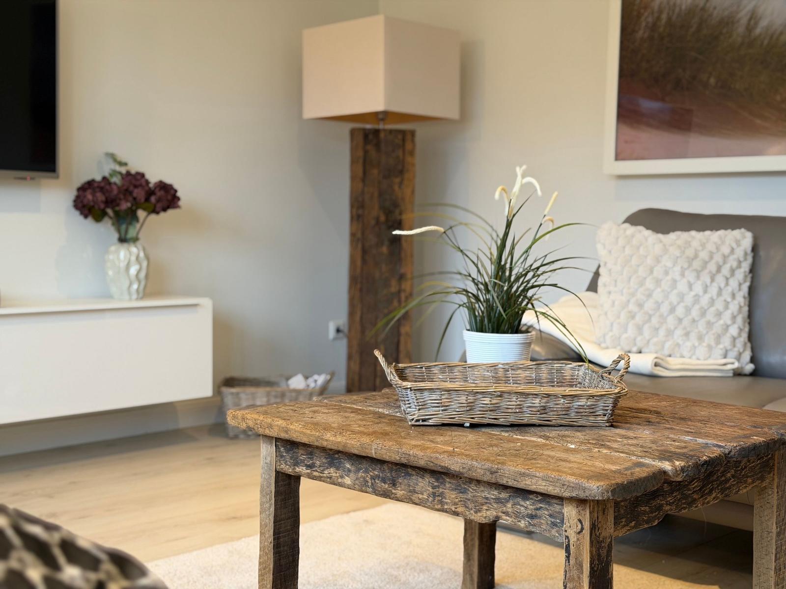 Holztisch mit Korb, Pflanze und Kissen im Wohnzimmer