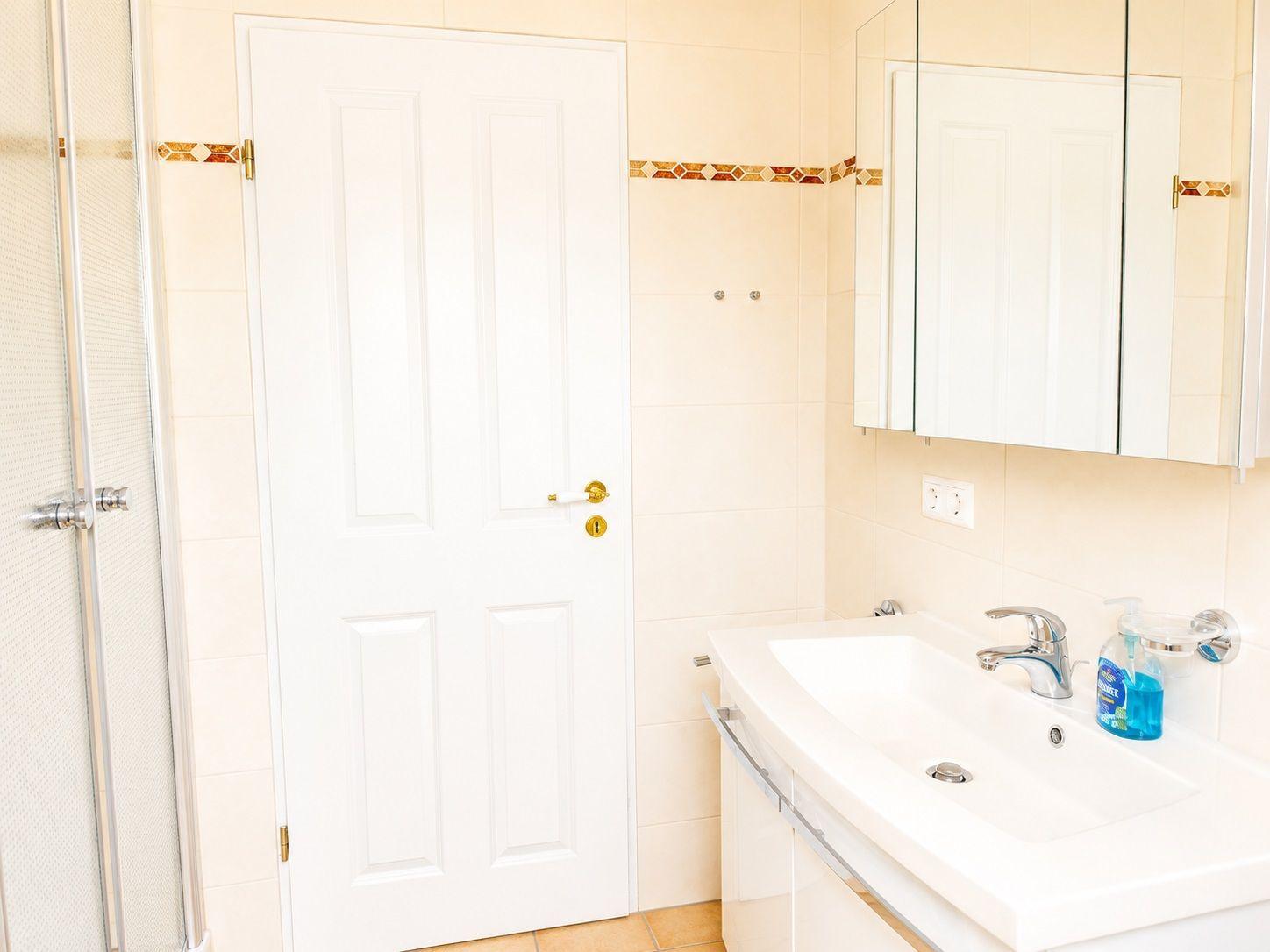 Badezimmer mit Waschbecken, Spiegelschrank und Dusche.