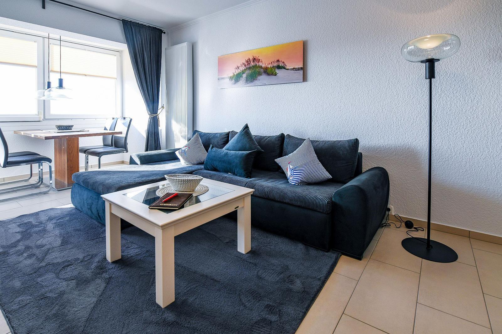 Ein Wohnzimmer mit einem dunkelblauen Sofa, einem weißen Tisch und einem Teppich.