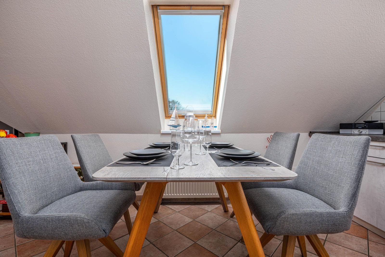 Essbereich mit Tisch und Stühlen unter Dachschrägen mit Fenster.
