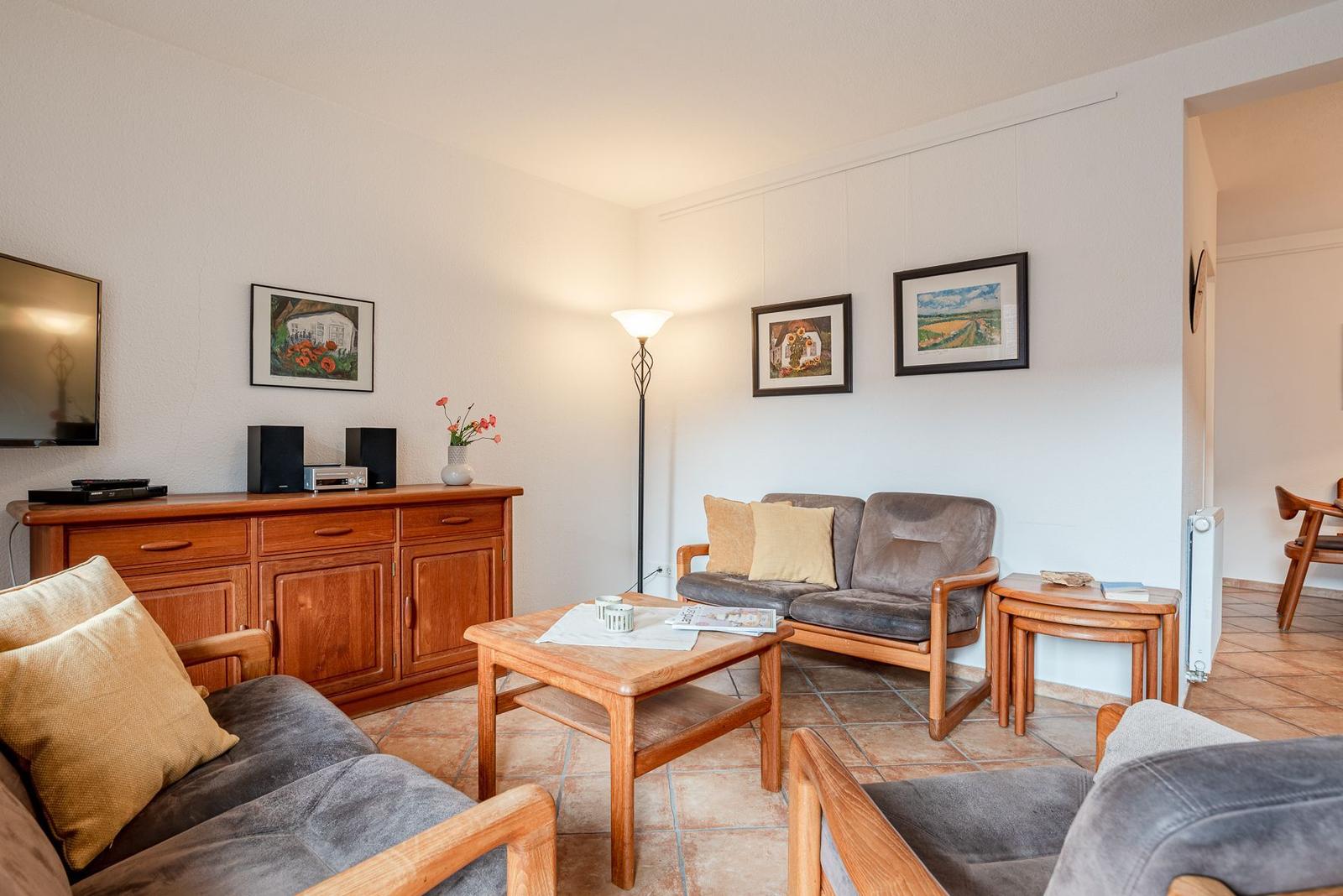 Wohnzimmer mit Sofa, Couchtisch und Fernseher an Wand